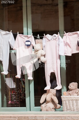 Image of baby clothing and teddy bear in window