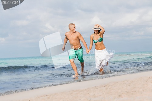 Image of young happy couple walking on beach sunset holiday