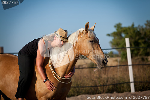 Image of young woman training horse outside in summer