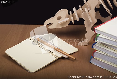 Image of Model of dinosaur, school board and pile books, notebook