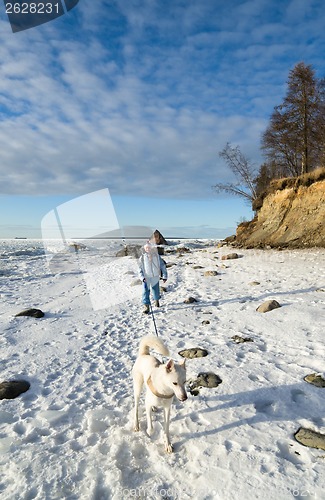 Image of Woman with a dog walk on a sunny winter day on the coast of the