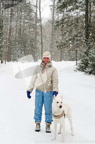 Image of Woman with a dog on a walk in the woods during a snowfall