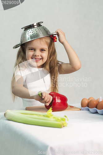 Image of Girl playing in cook put a colander on his head