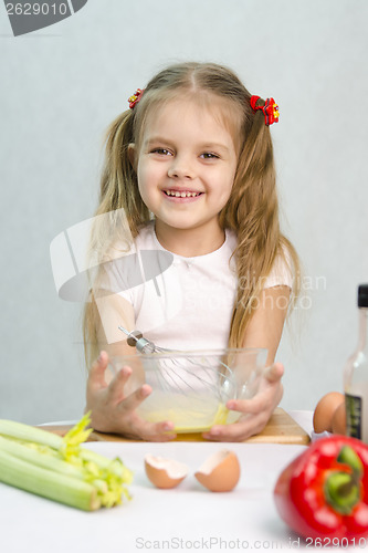 Image of Girl playing a cook churn whisk eggs in glass bowl