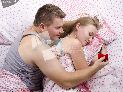 Image of young man gives a ring girl lying in bed