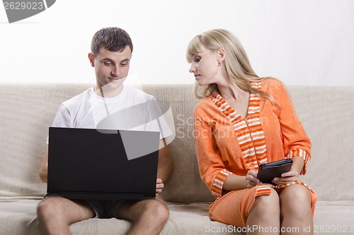 Image of guy with laptop sitting on couch, girl into his