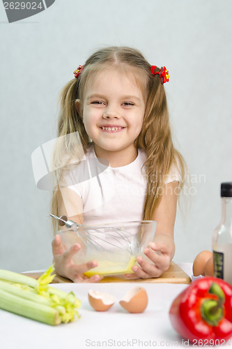 Image of Girl playing a cook churn whisk eggs in glass bowl