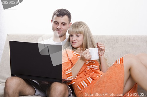 Image of guy sitting with his laptop on couch, girl Cup of tea