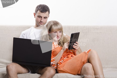 Image of boy and a girl sitting on couch with laptop
