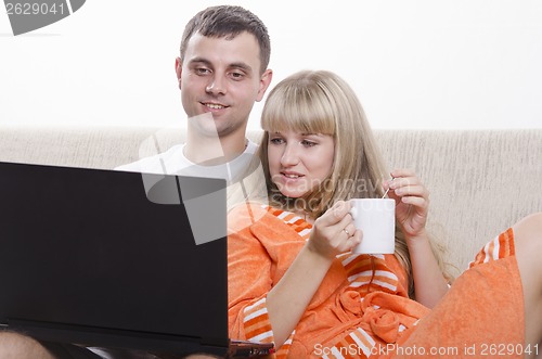 Image of guy sitting with his laptop on couch, girl Cup of tea