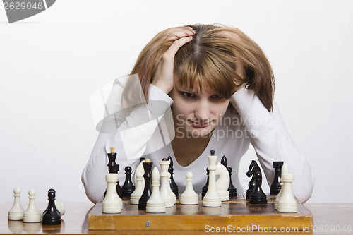 Image of Young girl to be considering a move during the game of chess