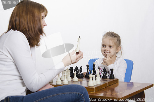 Image of Mother explains daughter purpose of the chess pieces