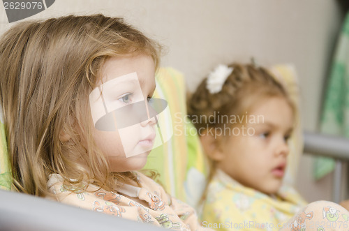 Image of Two children sit on couch and look to right