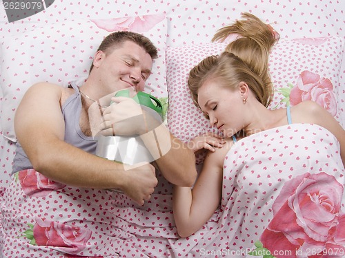 Image of couple in bed-husband sleeps with a barrel of beer