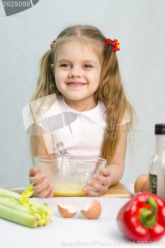 Image of Girl playing a cook churn whisk eggs in glass bowl