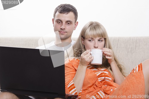 Image of guy sitting with his laptop on couch, girl Cup of tea