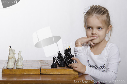 Image of Four-year-old girl with a sly look, plays chess