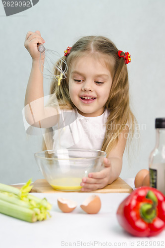 Image of Girl playing cook churn whisk eggs in a glass bowl