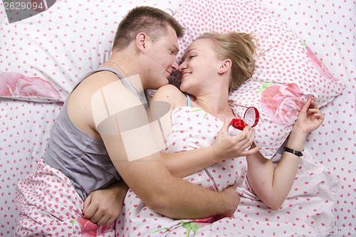 Image of young man gives a ring girl lying in bed