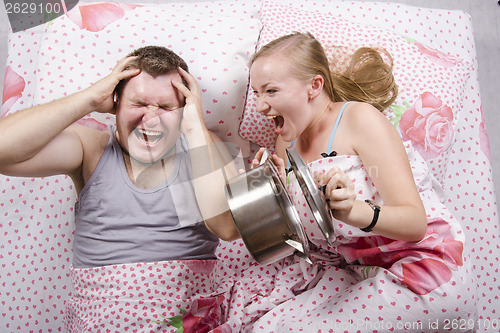 Image of She woke and frightened boy in bed, slamming lid on pan