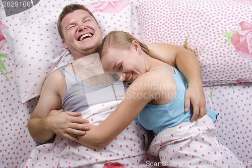 Image of Young couple lying in bed and laughs