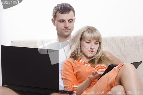 Image of boy and a girl sitting on couch with laptop