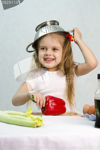 Image of Girl playing in cook put a colander on his head