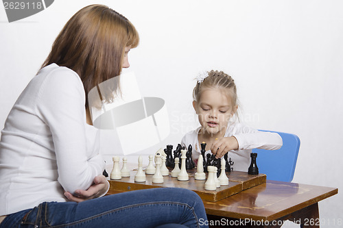 Image of Mother explains daughter purpose of the chess pieces