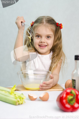 Image of Girl playing cook churn whisk eggs in a glass bowl