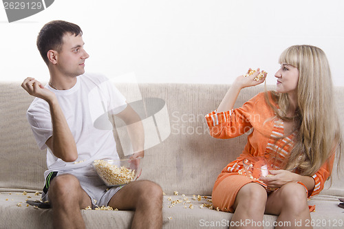 Image of Young couple sitting on the couch, and threw each other popcorn