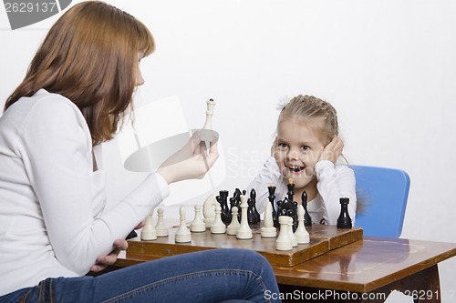 Image of Mother explains daughter purpose of the chess pieces
