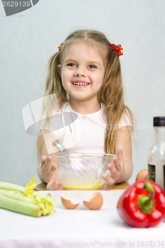 Image of Girl playing a cook churn whisk eggs in glass bowl