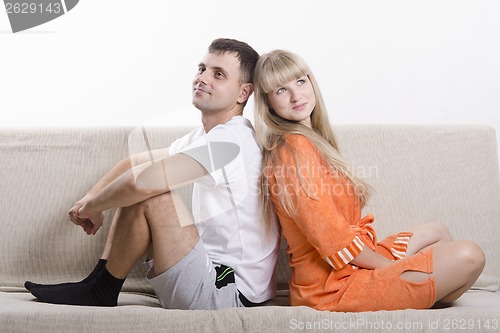 Image of Couple sitting on couch with his back to each other