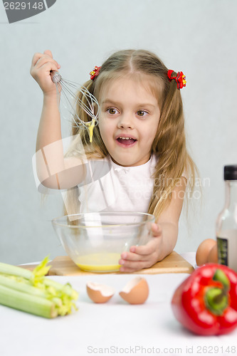 Image of Girl playing cook churn whisk eggs in a glass bowl