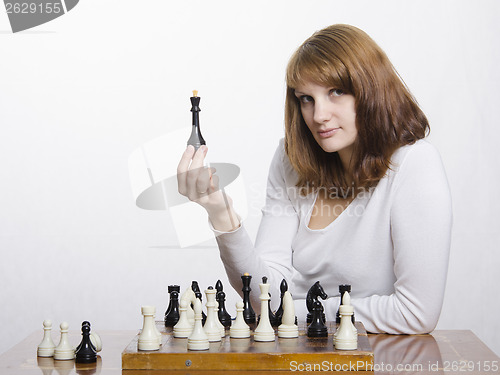 Image of young girl with a figure of  Queen, at chess Board