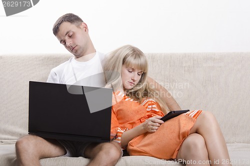 Image of Guy and girl asleep, sitting on couch with laptop