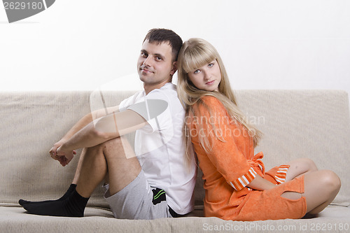 Image of Couple sitting on couch with his back to each other