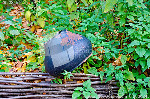 Image of Old cast iron pot on the fence