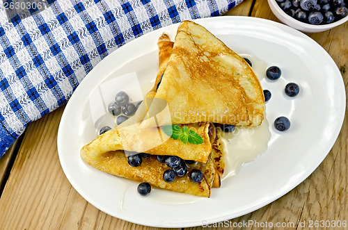 Image of Pancakes with blueberries and honey on the board