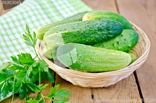 Image of Cucumbers with parsley in wicker basket on a board