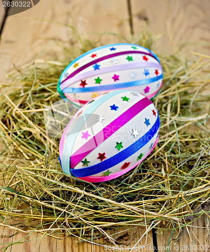 Image of Easter eggs with ribbons and sequins in the hay