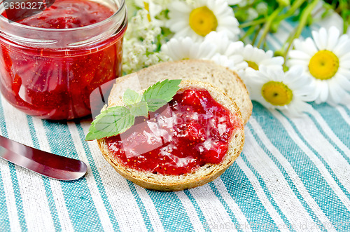 Image of Bread with strawberry jam and knife on a napkin