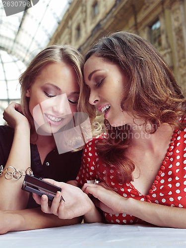 Image of two girlfriends look at the mobile phones