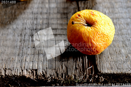 Image of wrinkled yellow apple on a board