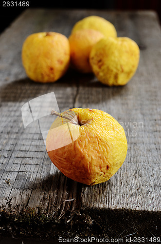 Image of wrinkled yellow apples on a wooden board 