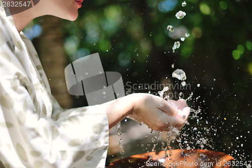 Image of splashing fresh water on woman hands