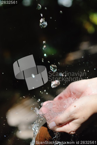 Image of splashing fresh water on woman hands