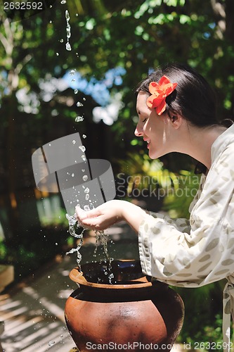 Image of splashing fresh water on woman hands