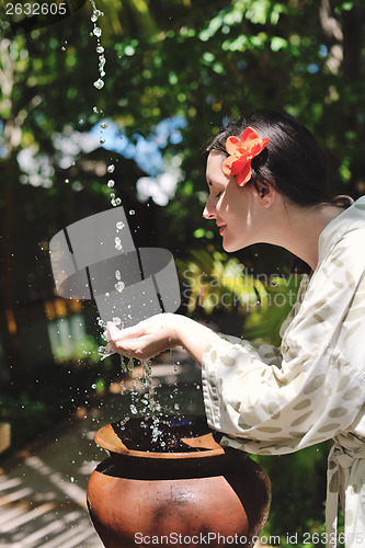 Image of splashing fresh water on woman hands