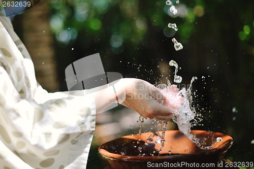 Image of splashing fresh water on woman hands